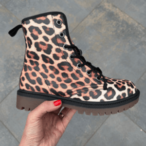 Hand with red nails holding a single Leopard Print Unisex Lace Up Combat Ankle Boot by Love Hype and Glory