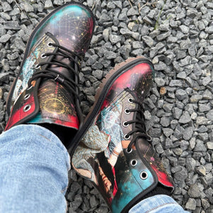 View of a person in jeans wearing The Sorceress Triple Moon Goddess Unisex Combat Boots by Love Hype and Glory outside on gravel path.