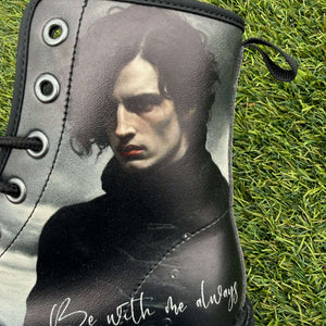 Mismatched Bronte Wuthering Heights boot with a printed design of Heathcliff's face and 'Be With Me Always' text on grass.