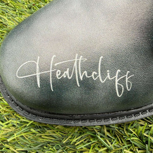 Mismatched Bronte Wuthering Heights boot  with 'Heathcliff' branding on grass